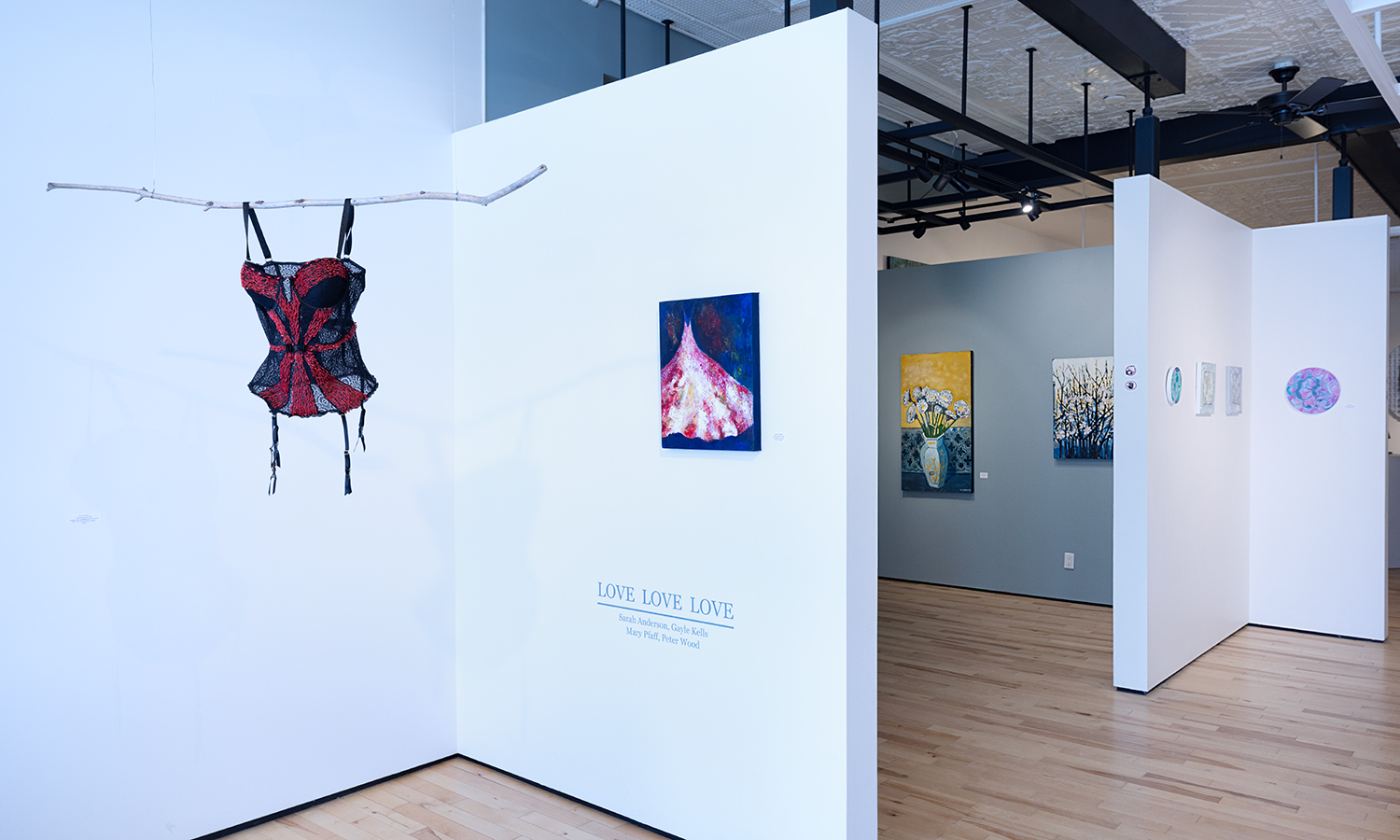 Photo of grey and white walls in a gallery with sparse artwork on them