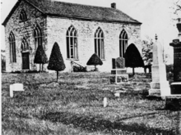 Black and white image of historic stone church and cemetery