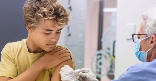 Photo of health care professional administering bandage to youth's arm