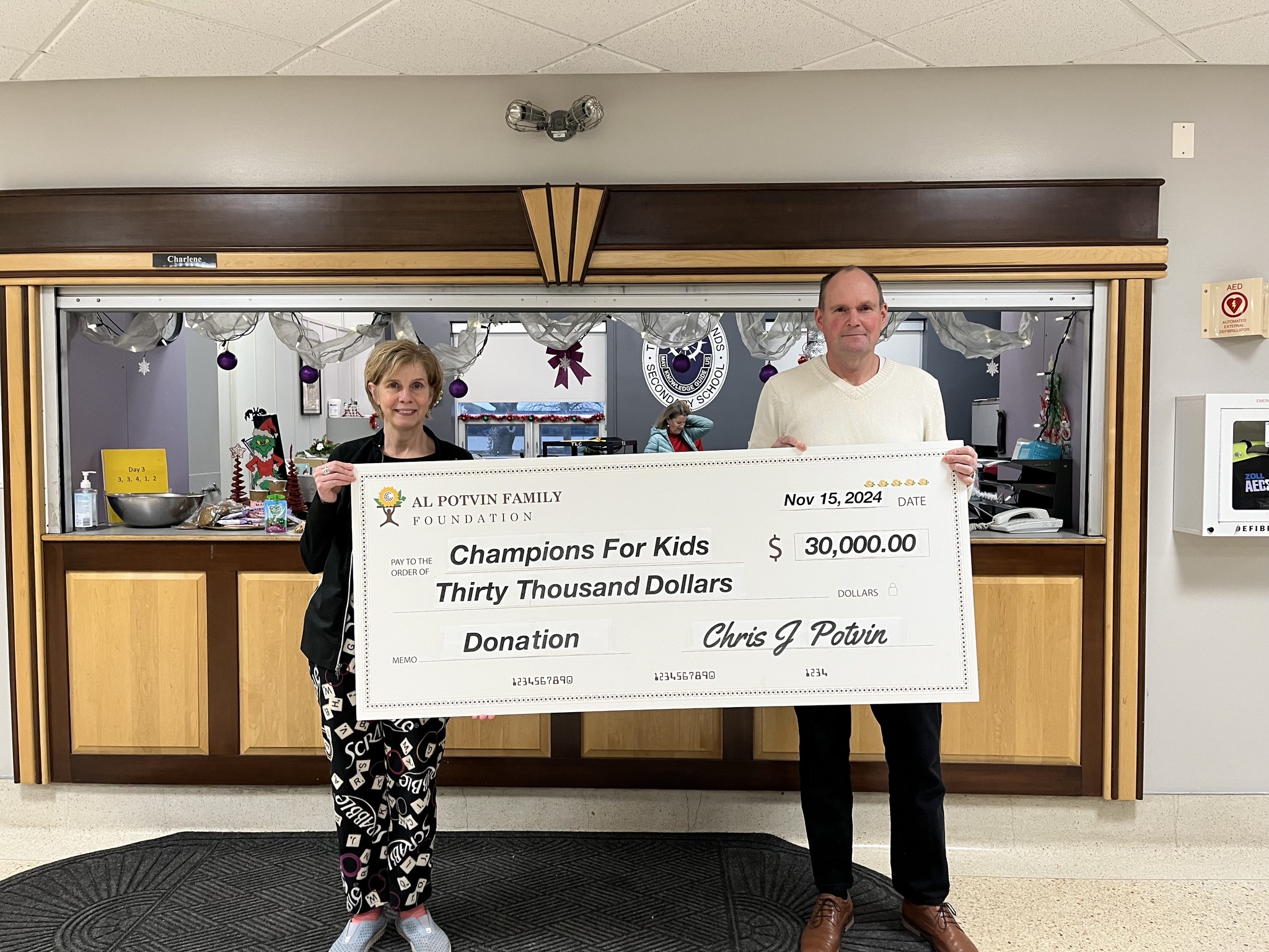 Two people pose for a photo holding a giant cheque