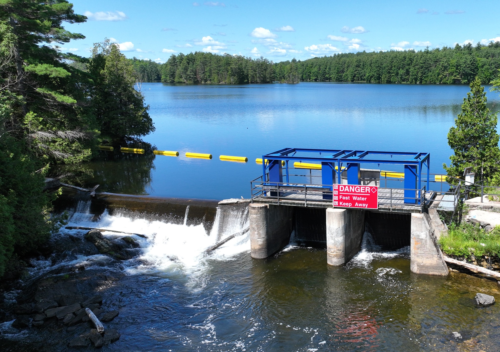 Photo of a dam on a lake with a red danger sign