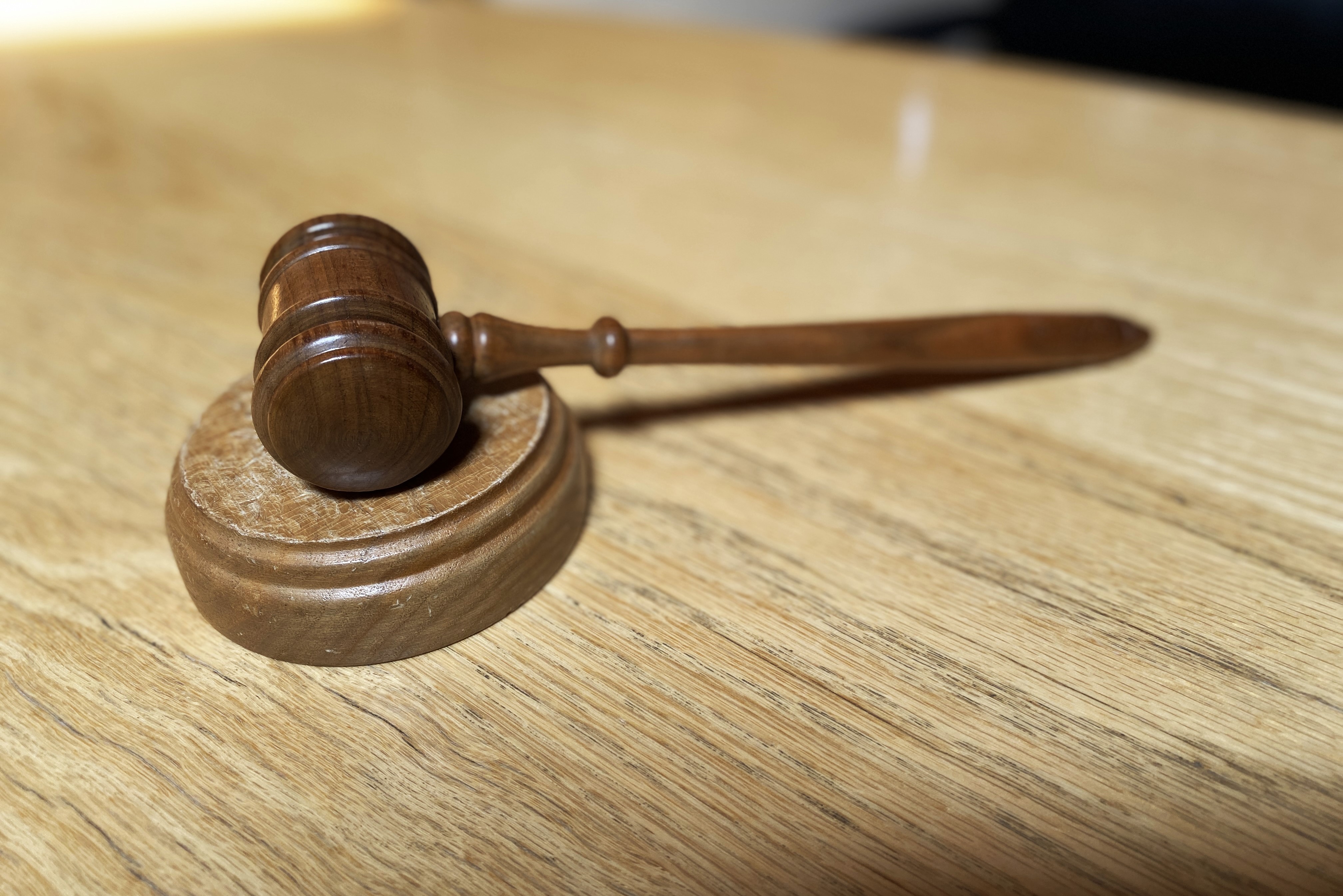 Wooden gavel rests on wooden desk