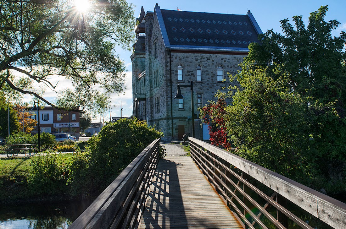 Wooden walking bridge over a river with stone building in the background