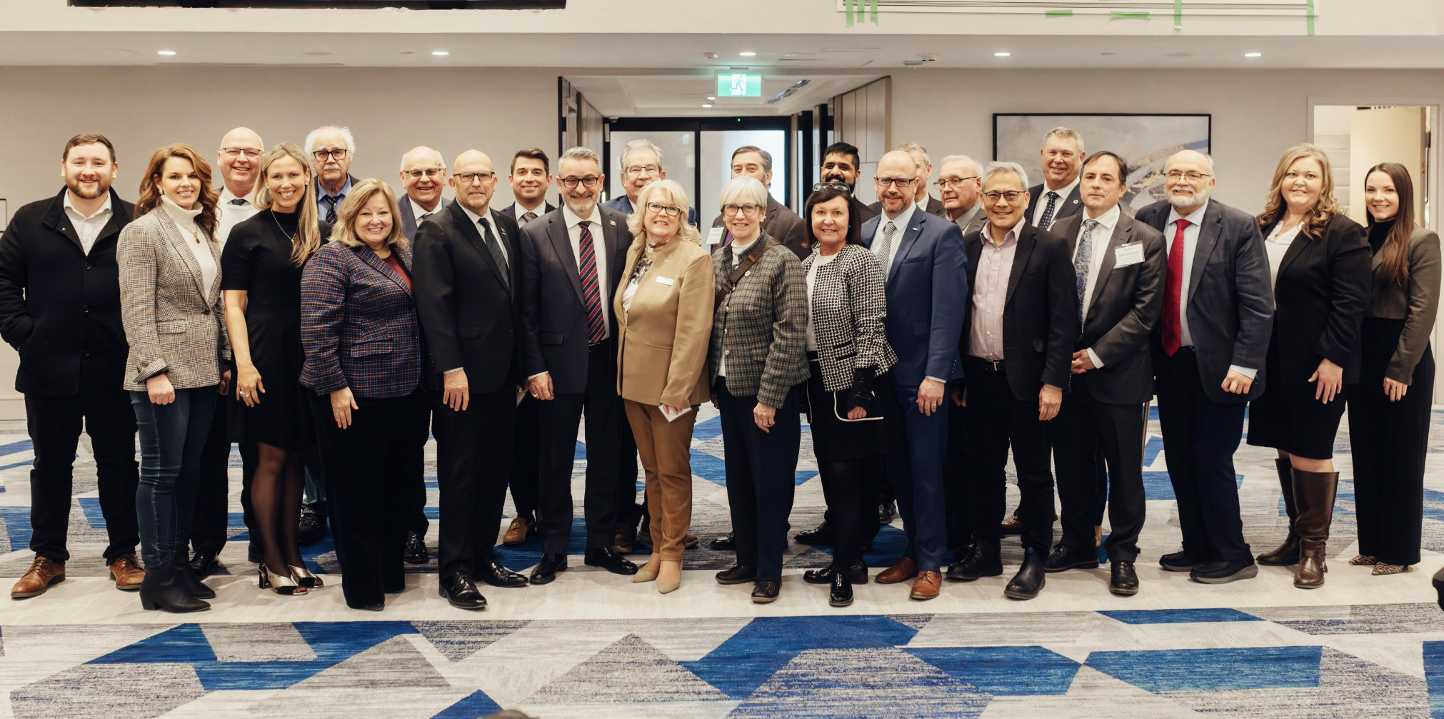 A large group of people in professional attire stand together for a photo